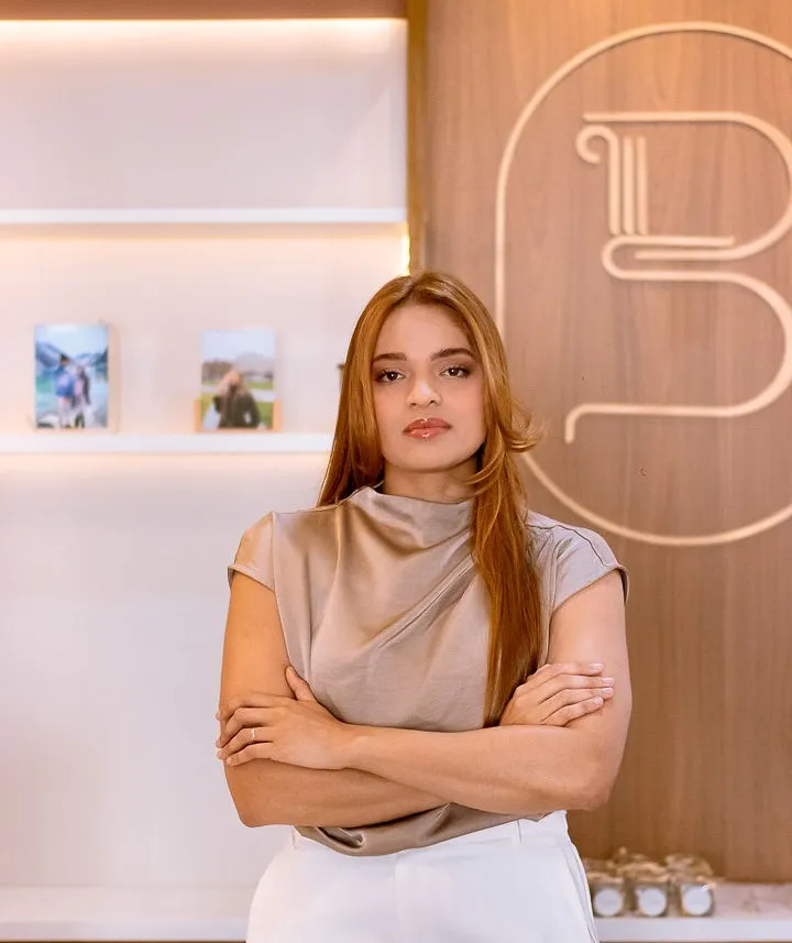 Bianca Saboia, advogada, de braços cruzados em frente ao logotipo do escritório